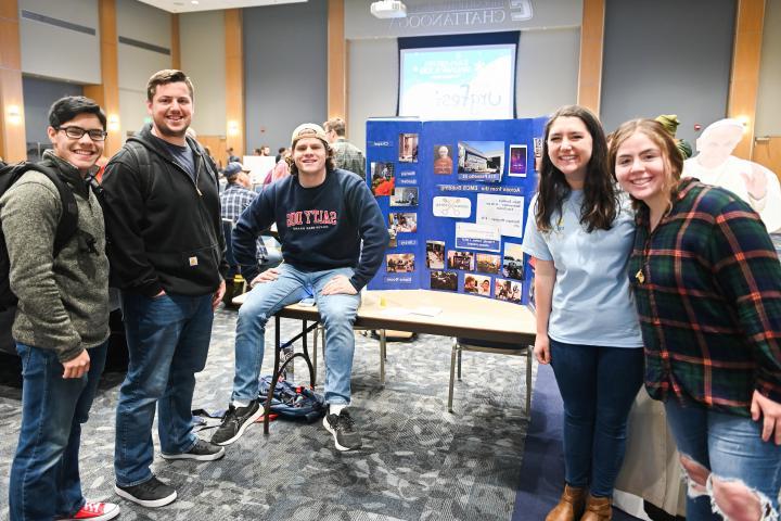 Student pose around and organization table at the winter organization fair. 