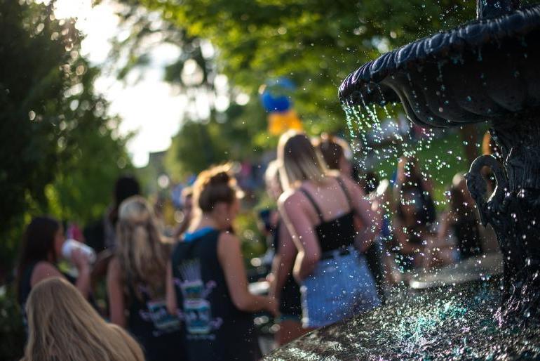 Artistic photo of water drops from a fountain, with students in a blurred background, shot on a Dutch Angle 