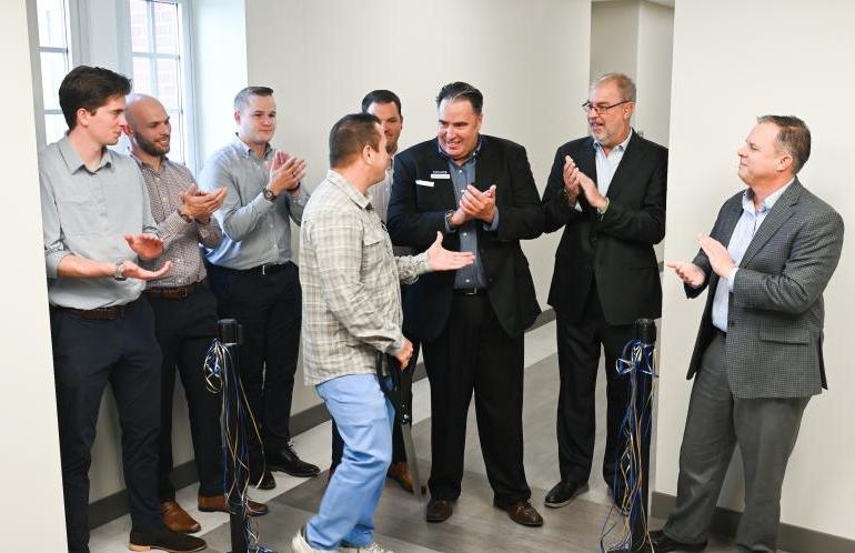 Eight people shaking hands after a ribbon cutting ceremony.