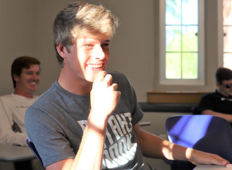 College student in gray t-shirt laughs during a sales class at the UTC Gary W. Rollins College of Business.